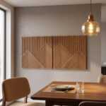 Geometric wood wall art panels above a wooden dining table with pendant light and upholstered chairs