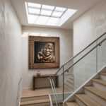 Abu Obaida Wall Art displayed in a modern stairway hallway above a wooden console table