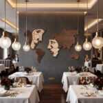 Elegant wooden world map wall accent with face line art on a dark accent wall in a luxurious fine dining restaurant.